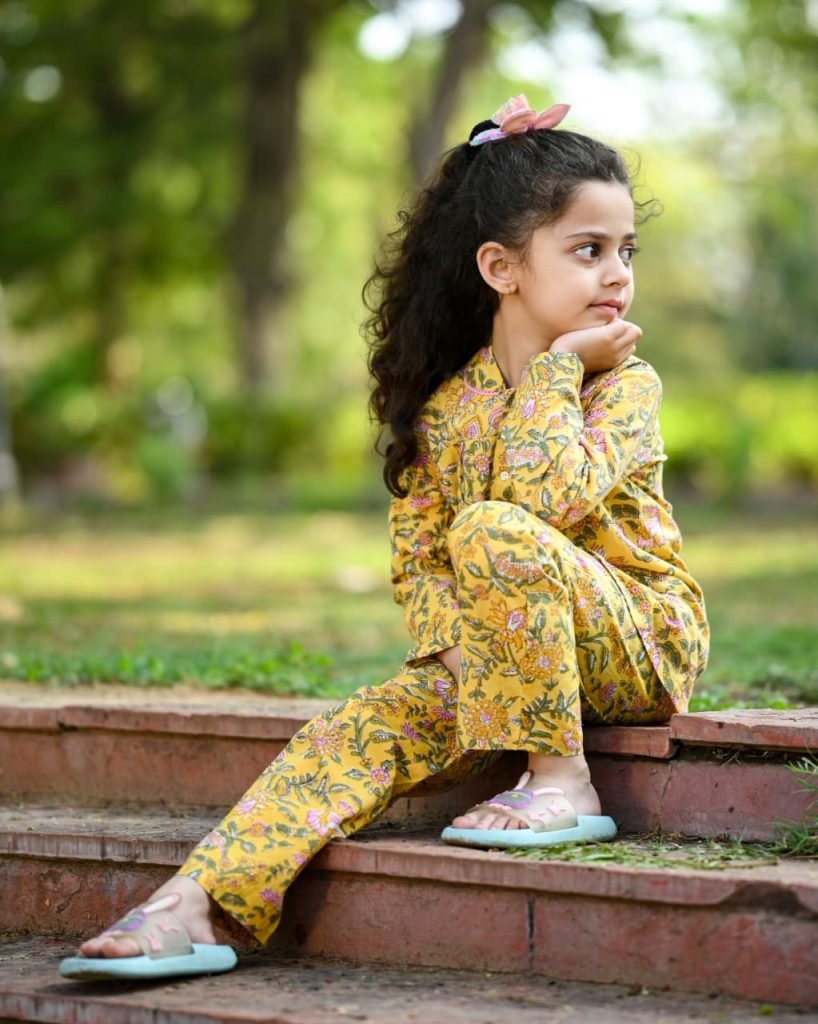 Little girl in a hand-screen printed yellow cotton night suit playing outdoors — NehaDhakaLabel